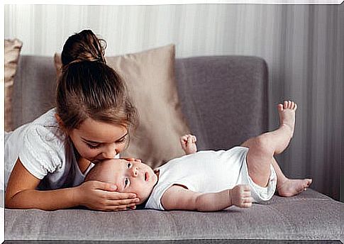 Older sister giving her baby brother lots of kisses.