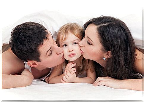 Parents giving their daughter many kisses.