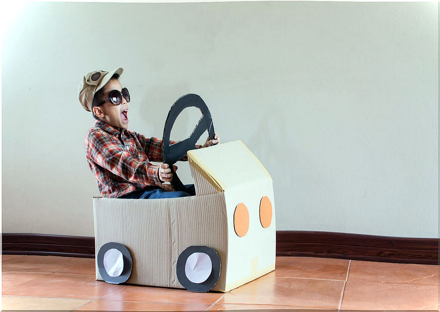 Child playing with a cardboard car, one of the ways to entertain children for hours.