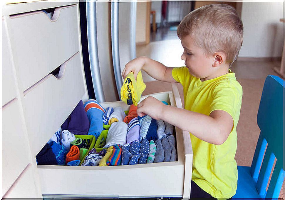 Independent boy putting his clothes in the closet.