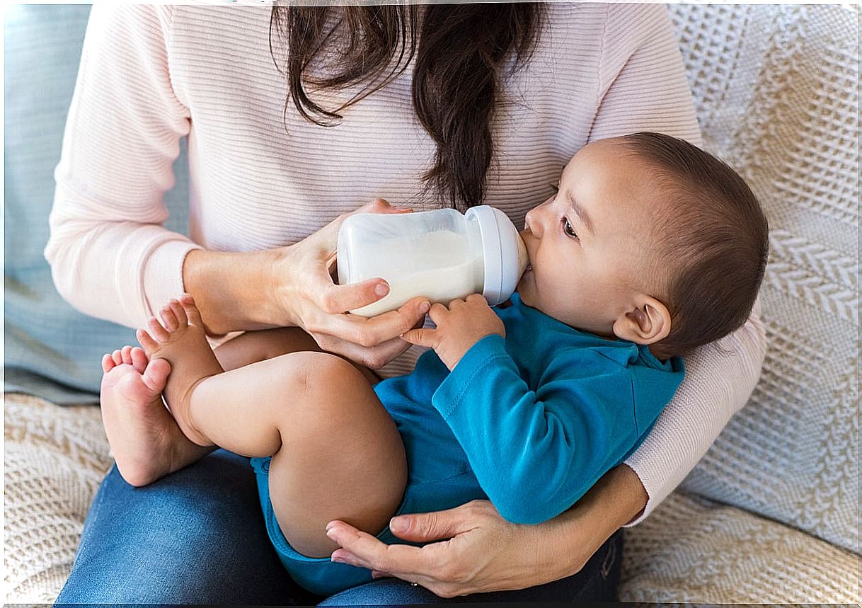 Mother giving the bottle to her son.