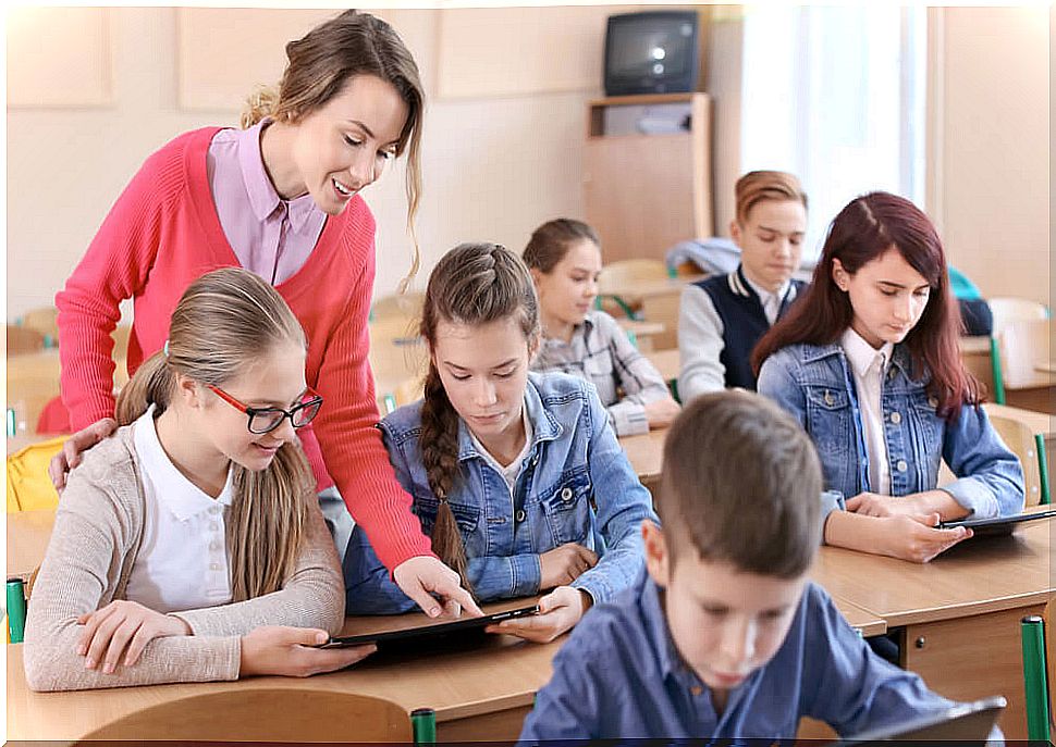 Students in class learning with tablets and the help of the teacher.