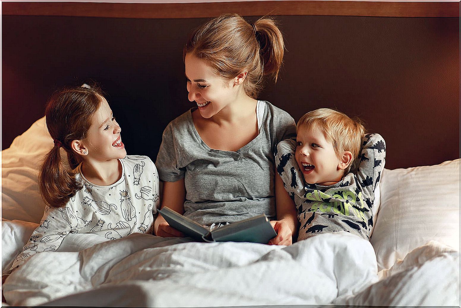 Mom reading a story to her children in bed before going to sleep.