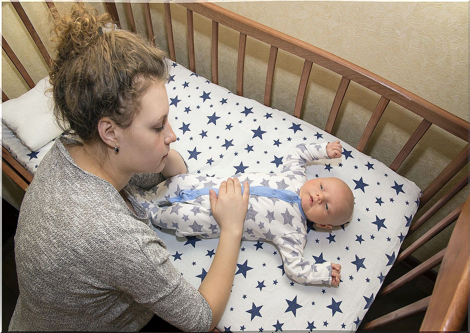 Mom looking at her newborn in the crib to try to get a good night's sleep as a family.