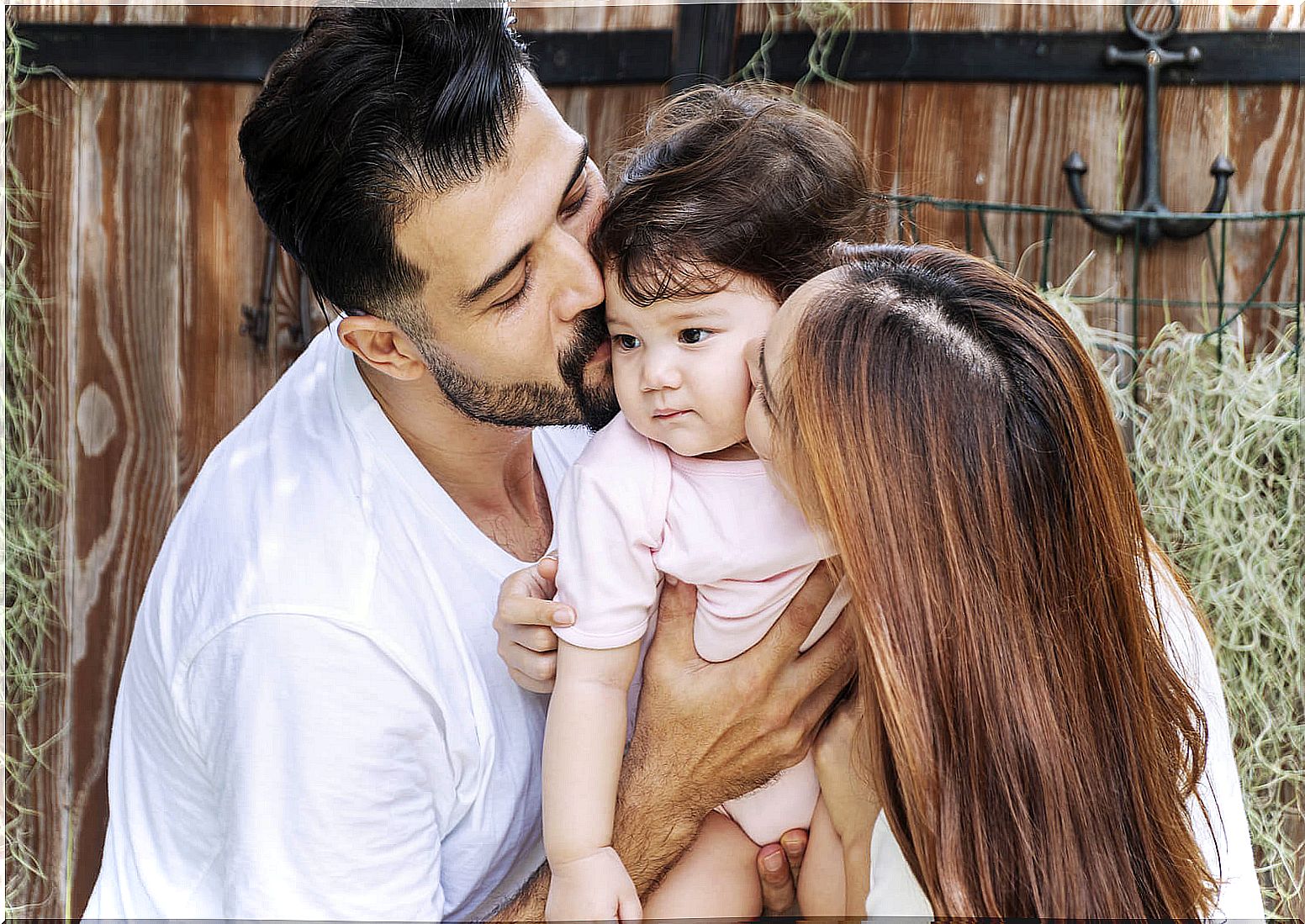 Parents kissing their baby.