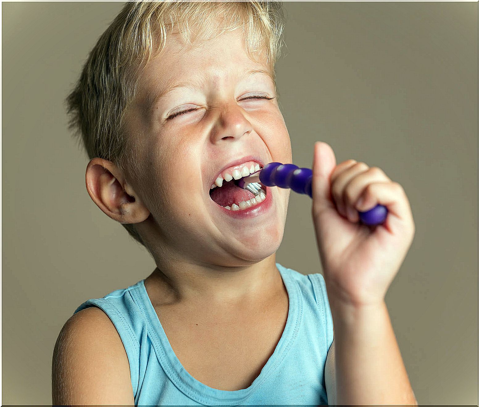 Child happily brushing teeth with fluoride paste.