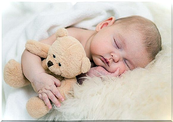 Baby asleep in his crib hugging a stuffed animal