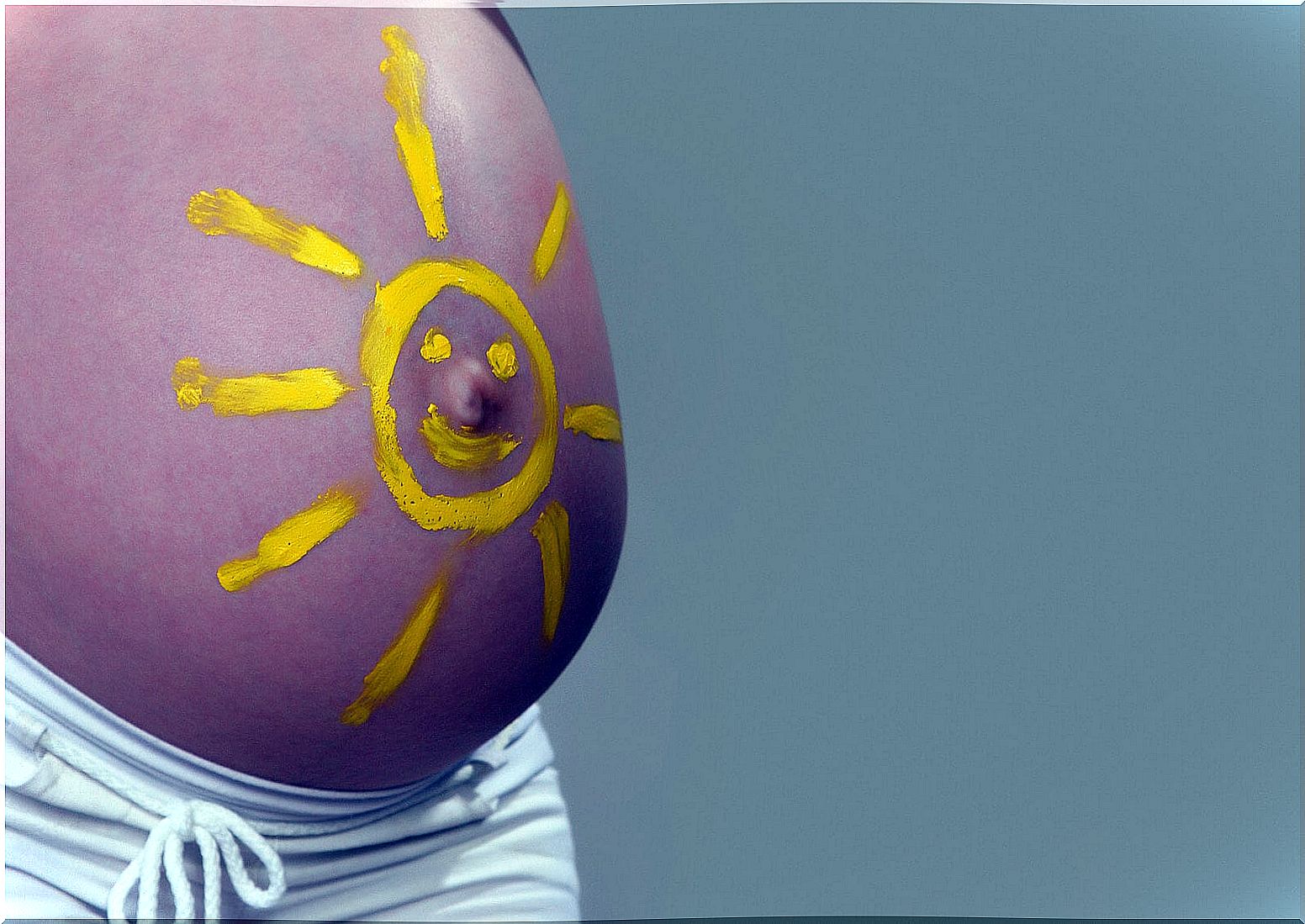 Belly in pregnancy painted with a sun.