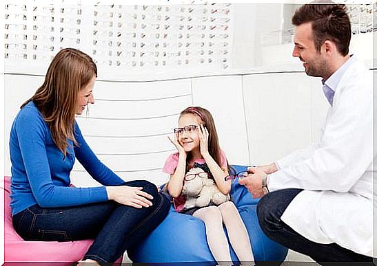 Mother visits optician, optometrist with her daughter.  Trying new glasses in optician store.