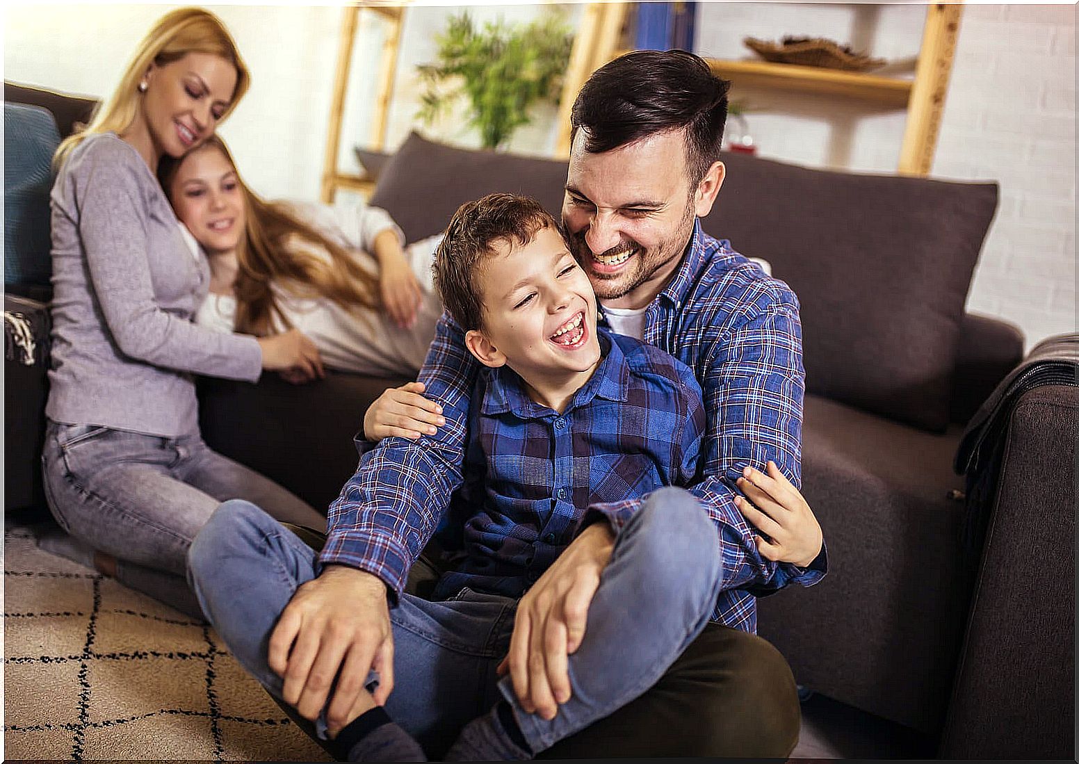 Parents playing with their children in the living room to show family support.